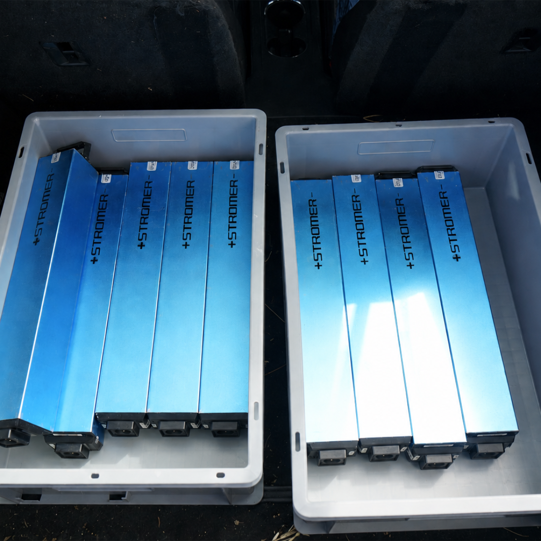 Zwei Transportboxen voller Stromer-E-Bike-Akkus im Kofferraum, bereit für Abholung und Rücklieferung durch upVolt