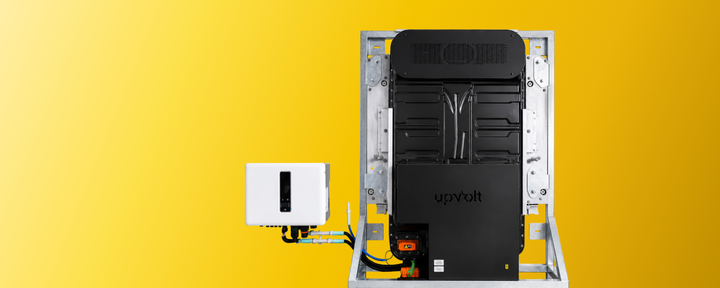 upVolt Second-Life-Energiespeicher für innen: schwarzes Batteriemodul im verzinkten Stahlrahmen mit upVolt-Logo, verbunden mit einem weissen Wechselrichter, vor gelbem Hintergrund.