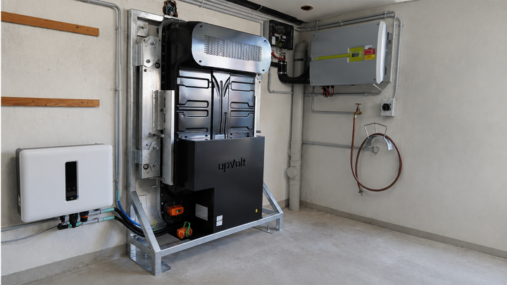 Installierter upVolt-Energiespeicher (Power Unit, 40 kWh) im Technikraum: schwarzes Batteriemodul im Stahlrahmen mit upVolt-Logo, daneben Wechselrichter an der Wand.