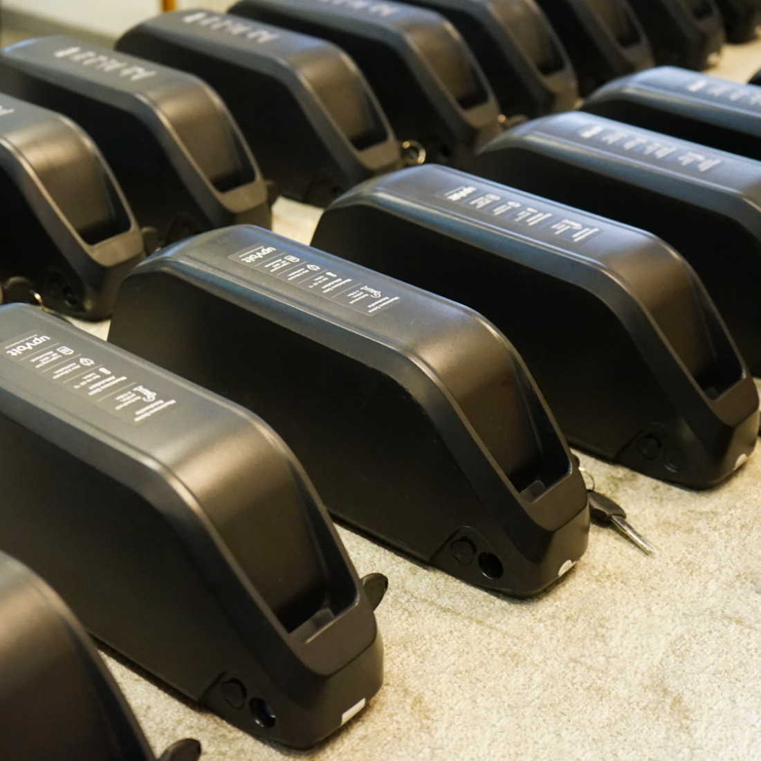 Refurbished E-Bike-Akkus mit UpVolt Branding aufgereiht in der Werkstatt Basel, bereit für den Versand